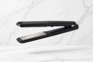Flat iron hair straightener with titanium plates on a marble background